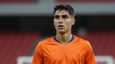 21-year-old athletic left-back, lean build, short dark hair, focused expression, head-and-shoulders shot, wearing a plain...