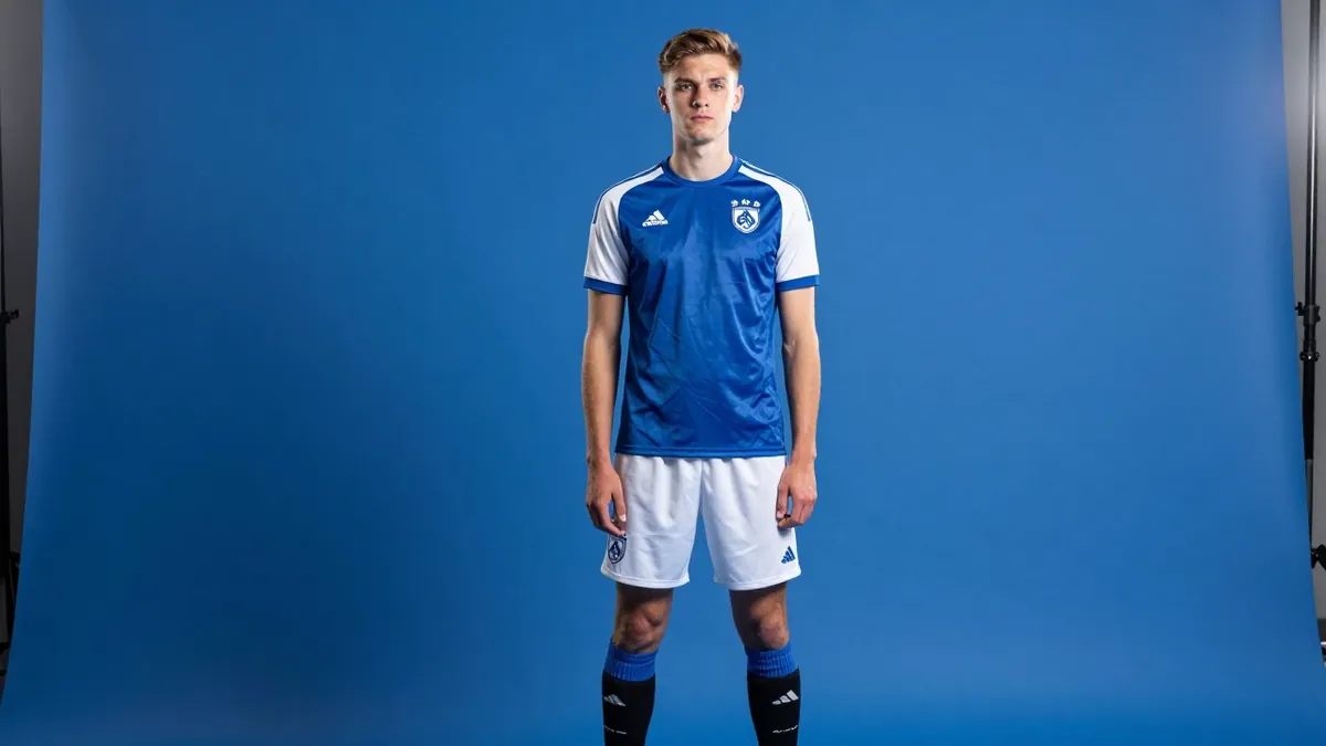 A photorealistic image of a young, anonymous defender of FC Volendam, with a serious expression, wearing a blue jersey...