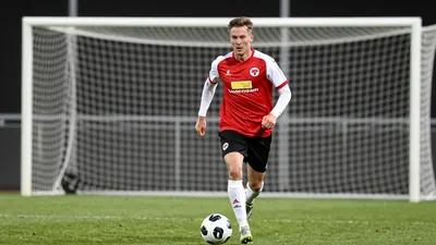 A photorealistic image of an anonymous FC Volendam player in a red jersey with white sleeves, black shorts and white...