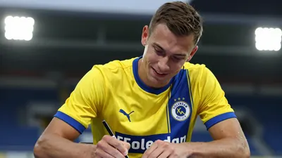A 31-year-old anonymous midfielder of FC Volendam, wearing a yellow and blue jersey with a white collar, is shown in a...