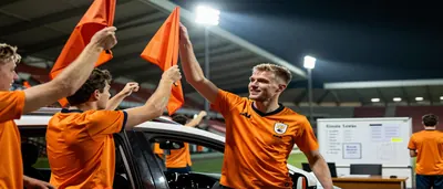 Kayne van Oevelen, mid-30s, athletic winger, sprinting with the ball on a sun-lit Dutch pitch, wearing a plain orange and...
